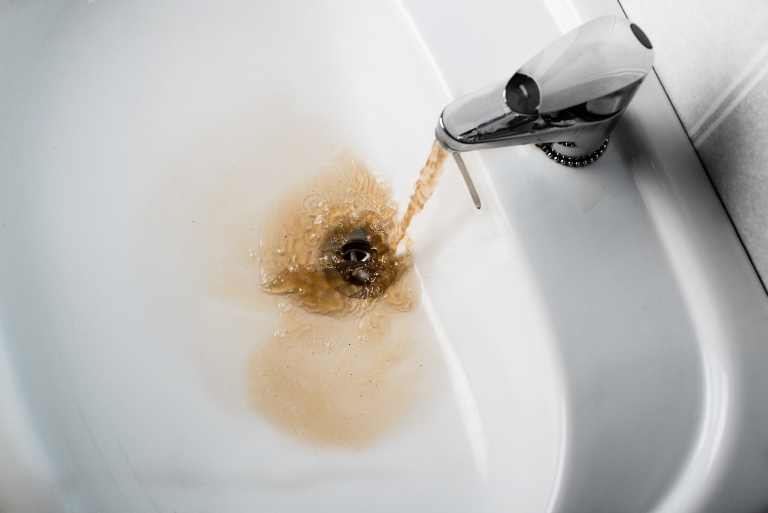 Brown water running into a sink