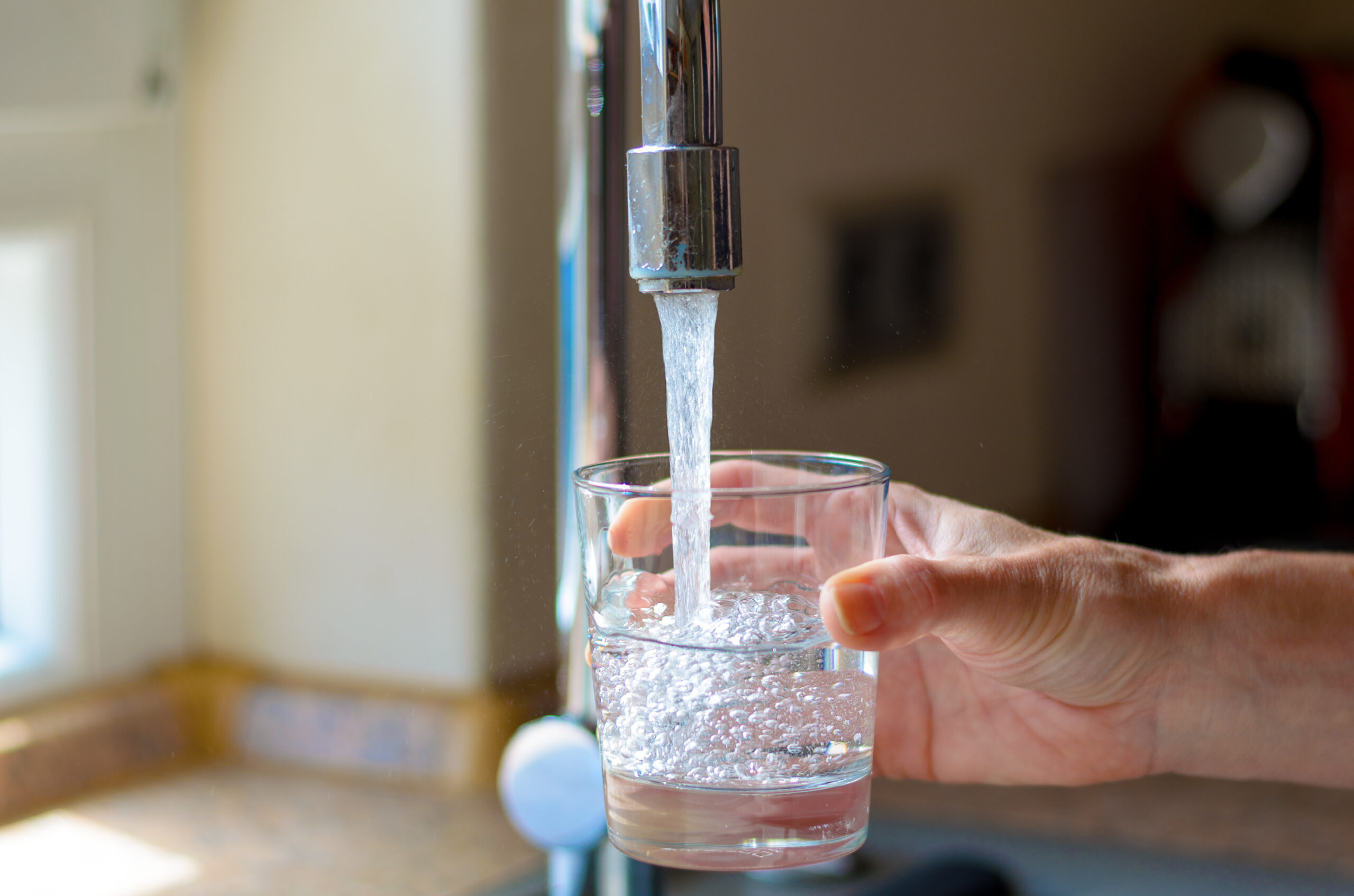 woman filling a glass of water from the faucet